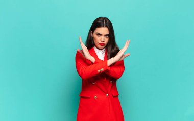 young pretty woman looking annoyed and sick of your attitude, saying enough! hands crossed up front, telling you to stop. business concept