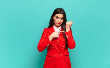 young pretty woman looking impatient and angry, pointing at watch, asking for punctuality, wants to be on time. business concept