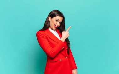 young pretty woman looking excited and surprised pointing to the side and upwards to copy space. business concept