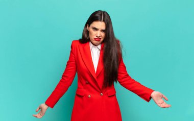 young pretty woman feeling clueless and confused, having no idea, absolutely puzzled with a dumb or foolish look. business concept