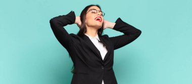 young pretty woman smiling and feeling relaxed, satisfied and carefree, laughing positively and chilling. business concept