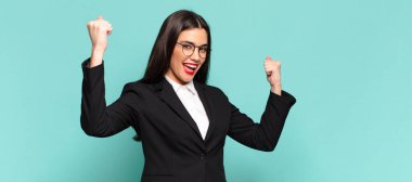 young pretty woman shouting triumphantly, looking like excited, happy and surprised winner, celebrating. business concept