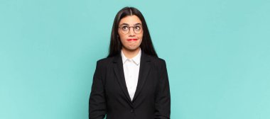 young pretty woman looking puzzled and confused, wondering or trying to solve a problem or thinking. business concept
