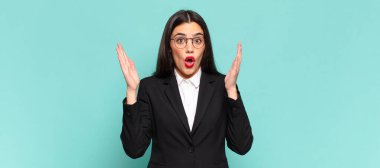 young pretty woman looking shocked and astonished, with jaw dropped in surprise when realizing something unbelievable. business concept