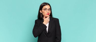 young pretty woman looking serious, confused, uncertain and thoughtful, doubting among options or choices. business concept