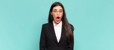 young pretty woman feeling terrified and shocked, with mouth wide open in surprise. business concept