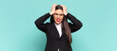 young pretty woman feeling stressed and anxious, depressed and frustrated with a headache, raising both hands to head. business concept