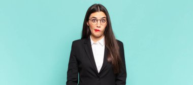 young pretty woman looking puzzled and confused, biting lip with a nervous gesture, not knowing the answer to the problem. business concept