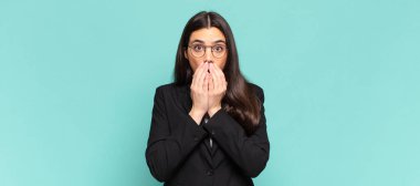 young pretty woman feeling worried, upset and scared, covering mouth with hands, looking anxious and having messed up. business concept