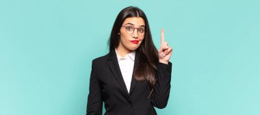 young pretty woman feeling like a genius holding finger proudly up in the air after realizing a great idea, saying eureka. business concept