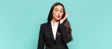 young pretty woman feeling shocked and astonished holding face to hand in disbelief with mouth wide open. business concept