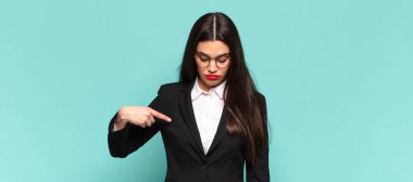 Genç ve güzel bir kadın neşeyle gülümsüyor, yere bakıyor ve göğsüne işaret ediyor. iş kavramı