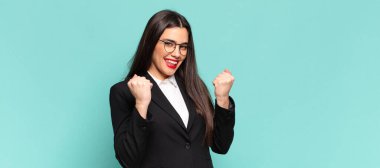 Genç ve güzel bir kadın zaferle bağırıyor, gülüyor, mutlu ve heyecanlı hissediyor ve başarıyı kutluyor. iş kavramı