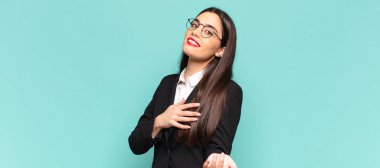 Genç ve güzel bir kadın mutlu ve aşık, bir eli kalbinin yanında, diğer eli önde uzanmış şekilde gülümsüyor. iş kavramı