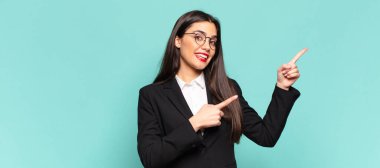 Genç, güzel bir kadın kendini neşeli ve şaşırmış hissediyor. Şok olmuş bir ifadeyle gülümsüyor ve bir tarafı işaret ediyor. iş kavramı