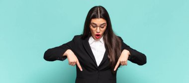 Genç, güzel bir kadın şok olmuş, ağzı açık ve şaşırmış, inançsızlık ve şaşkınlık içinde bakıyor ve onu işaret ediyor. iş kavramı