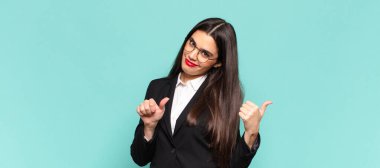 Genç ve güzel bir kadın neşeyle gülümsüyor ve yan taraftaki fotokopi alanını işaret ediyor, mutlu ve tatmin olmuş hissediyor. iş kavramı