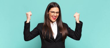 Genç ve güzel bir kadın öfkeli bir ifadeyle ya da yumruklarıyla başarıyı kutlarken agresif bir şekilde bağırıyor. iş kavramı