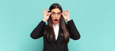 Genç, güzel bir kadın şaşkın, şaşırmış ve şaşırmış hissediyor. Elinde şaşkın ve inanmayan bir bakışla gözlük tutuyor. iş kavramı
