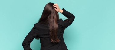 Genç, güzel bir kadın bilgisiz ve kafası karışık hissediyor, bir çözüm düşünüyor, eli kalçasında, diğeri kafasında, dikiz aynasından bakıyor. iş kavramı