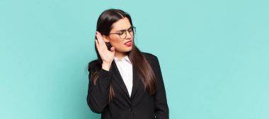 Genç ve güzel bir kadın ciddi ve meraklı görünüyor, dinliyor, gizli bir konuşma veya dedikodu duymaya çalışıyor, kulak misafiri oluyor. iş kavramı