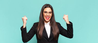 Genç, güzel bir kadın mutlu, pozitif ve başarılı hissediyor zaferi, başarıları ya da iyi şansı kutluyor. iş kavramı