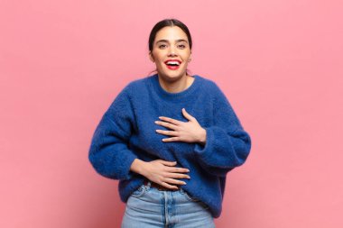 Genç ve güzel bir kadın komik bir şakaya yüksek sesle gülüyor, mutlu ve neşeli hissediyor, eğleniyor.