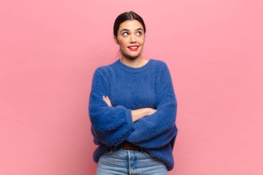 Genç, güzel bir kadın kendini mutlu, gururlu ve umutlu hissediyor, merak ediyor veya düşünüyor, çapraz kollarla boşluğu doldurmaya çalışıyor.