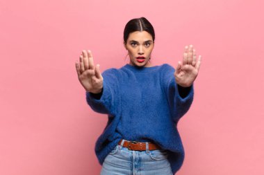 Genç ve güzel bir kadın ciddi, mutsuz, kızgın ve hoşnutsuz görünüyor. Ya da her iki avucunun içinde de dur diyor.