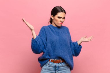 Şaşkın, kafası karışmış ve stresli görünen genç bir kadın. Farklı seçenekler arasında merak ediyor, kararsız.