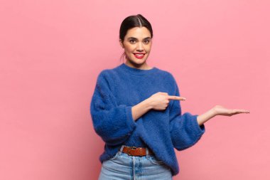 Genç, güzel bir kadın gülümsüyor, mutlu, kaygısız ve tatmin olmuş hissediyor, fotokopi alanındaki konsepte veya fikre işaret ediyor.