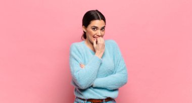 Genç ve güzel bir kadın ciddi, düşünceli ve endişeli, elleri çenesine bastırılmış bir şekilde yan bakıyor.