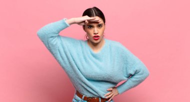 Genç, güzel bir kadın şaşkınlık ve şaşkınlık içinde bakıyor. Alnı açık, uzaklara bakıyor, izliyor ya da arıyor.