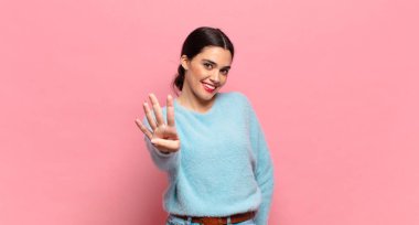 Genç, güzel bir kadın gülümsüyor ve arkadaş canlısı görünüyor. Dört ya da dört numarayı gösteriyor. Elleri önde, geri sayıyor.