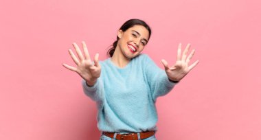 Genç ve güzel bir bayan gülümsüyor ve arkadaş canlısı görünüyor, onuncu veya onuncu numarayı gösteriyor, eli önde, geriye doğru sayıyor.