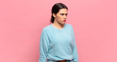 Genç, güzel bir kadın üzgün, üzgün ya da kızgın ve olumsuz bir tavır takınıyor, anlaşmazlık içinde kaşlarını çatıyor.