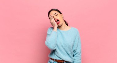 Genç ve güzel bir kadın uykulu görünüyor, sıkılmış ve esniyor, baş ağrısı ve yüzünün yarısını kaplayan bir eliyle