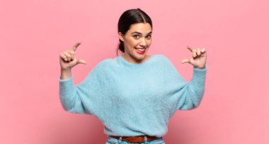 Genç, güzel bir kadın iki eliyle kendi gülüşünü çiziyor, olumlu ve mutlu görünüyor, sağIık kavramı.