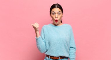 Genç ve güzel bir kadın inançsızlıktan şaşkın şaşkın bakıyor, yan taraftaki objeyi işaret ediyor ve diyor ki: