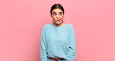 Genç ve güzel bir kadın kafası karışmış görünüyor, merak ediyor veya bir sorunu çözmeye çalışıyor ya da düşünüyor.