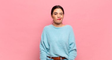 Genç ve güzel bir kadın mutlu ve arkadaş canlısı görünüyor, gülümsüyor ve sana olumlu bir tavırla göz kırpıyor.