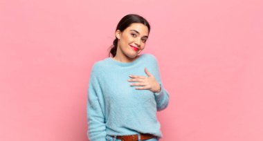 Genç ve güzel bir kadın şok olmuş ve şaşırmış hissediyor, gülümsüyor, el ele tutuşuyor, o kişi olmaktan mutlu ya da minnettarlık gösteriyor.