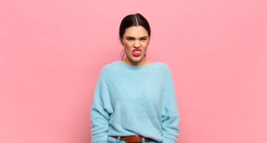 Genç, güzel bir kadın şaşkın ve şaşkın hissediyor, aptal, sersemlemiş bir ifadeyle beklenmedik bir şeye bakıyor.