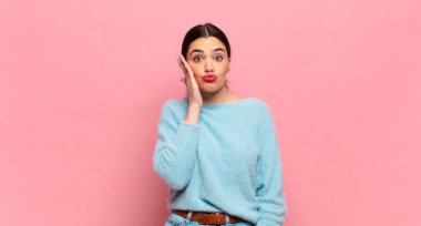 Genç, güzel bir kadın, ağzı açık bir şekilde yüz yüze inanmayarak şok olmuş ve hayrete düşmüş hissediyor.