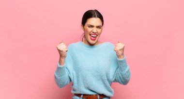 Genç ve güzel bir kadın zaferle bağırıyor, gülüyor, mutlu ve heyecanlı hissediyor başarıyı kutlarken.