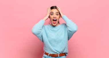 Genç ve güzel bir kadın el ele tutuşuyor, ağzı açık, son derece şanslı, şaşırmış, heyecanlı ve mutlu hissediyor.