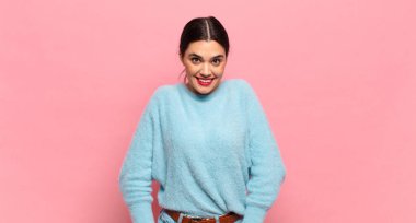 Genç ve güzel bir kadın neşeli ve tesadüfen gülümsüyor. Olumlu, mutlu, kendinden emin ve rahat bir ifadeyle.