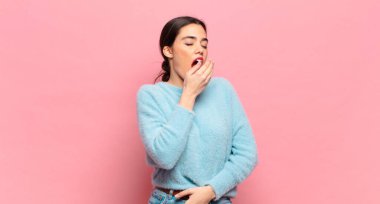 Genç ve güzel bir kadın sabahın erken saatlerinde uykulu, yorgun ve sıkkın bir şekilde esniyor.