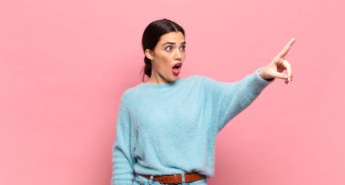 Genç, güzel bir kadın şaşkın ve şaşırmış hissediyor. Şaşırmış ve ağzı açık bir şekilde hayranlıkla yukarı bakıyor.