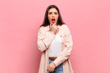 Ağzı ve gözleri açık, eli çenesinde genç ve güzel bir kadın. Hoş olmayan bir şok geçiriyor.